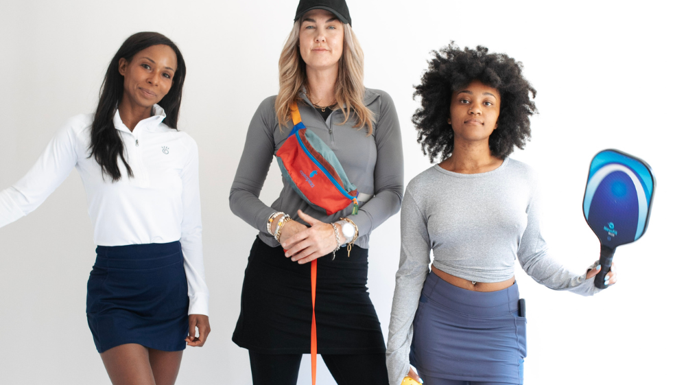 Three women of diverse ages pose together, showcasing trendy athleisure attire for all ages.