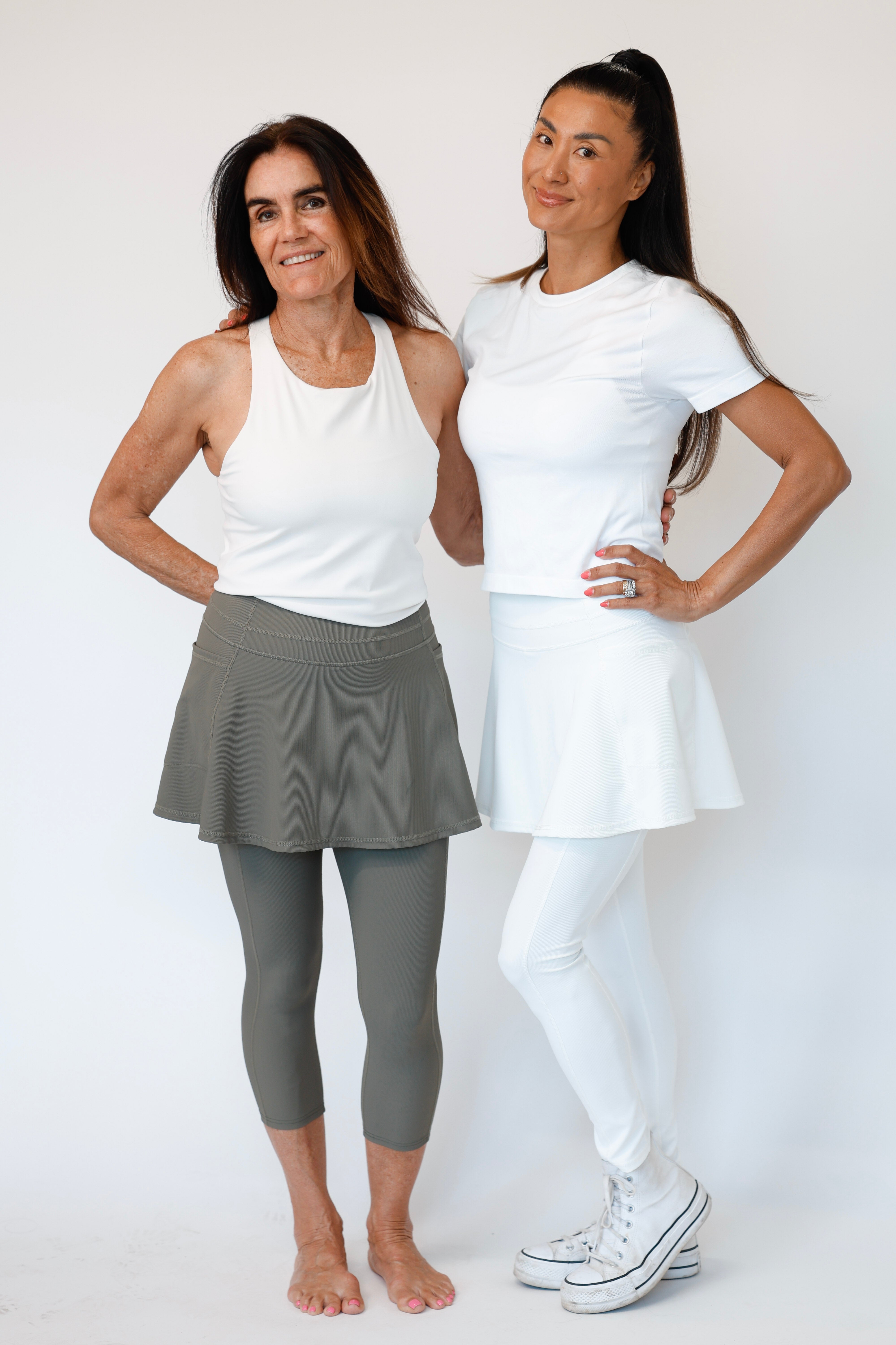 Two women wearing athletic wear standing against a white background