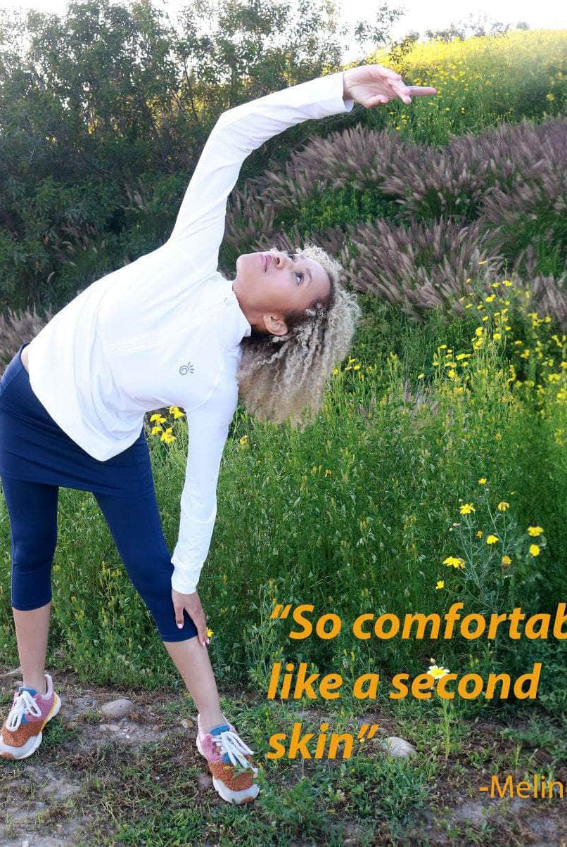 model wearing capris length blueberry colored skirted leggings in a field of flowers.