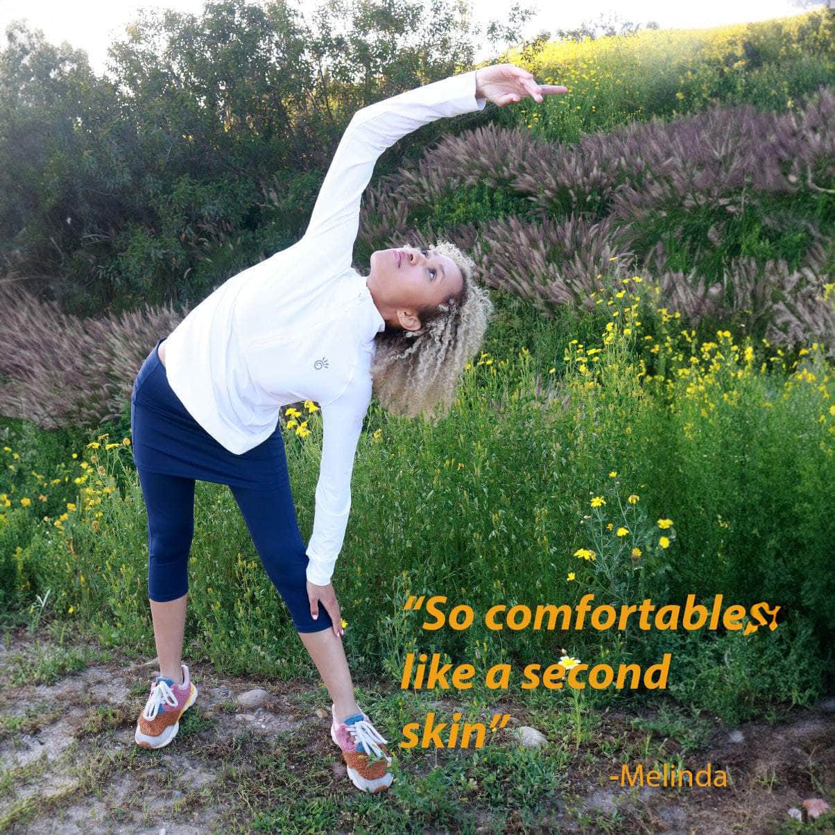 model wearing capris length blueberry colored skirted leggings in a field of flowers.