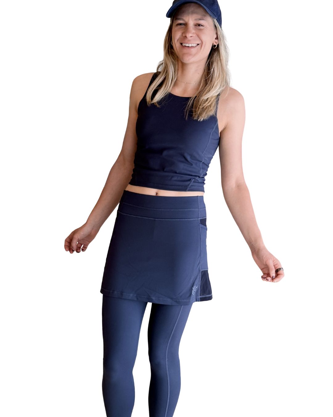 Woman wearing a midnight navy athletic outfit with a Midnight Navy Blue shelf bra top and skirted legging on a white background