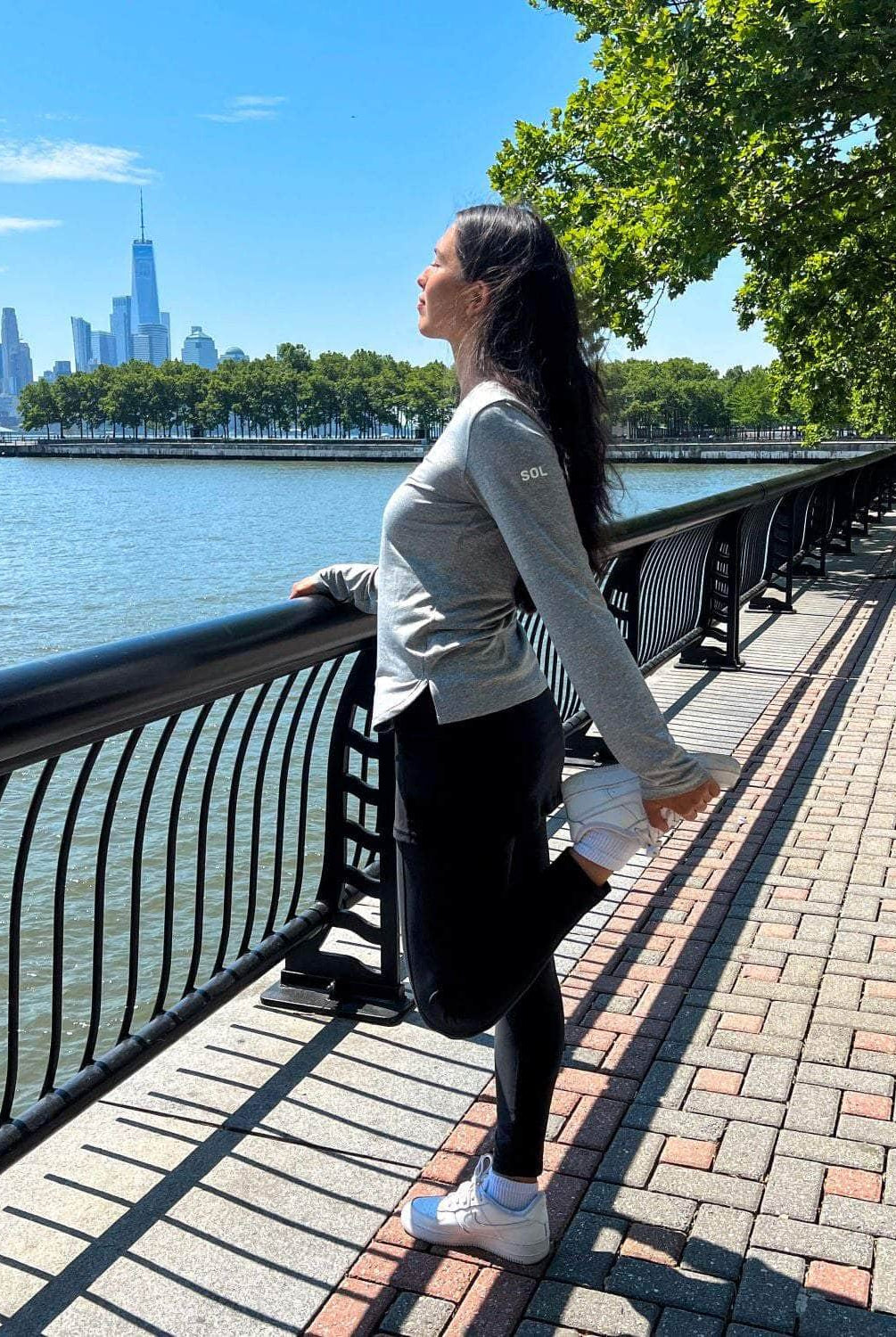 Black ankle length skirted leggings modeled by woman holding handrail near harbor also wearing our grey active sol shirt.