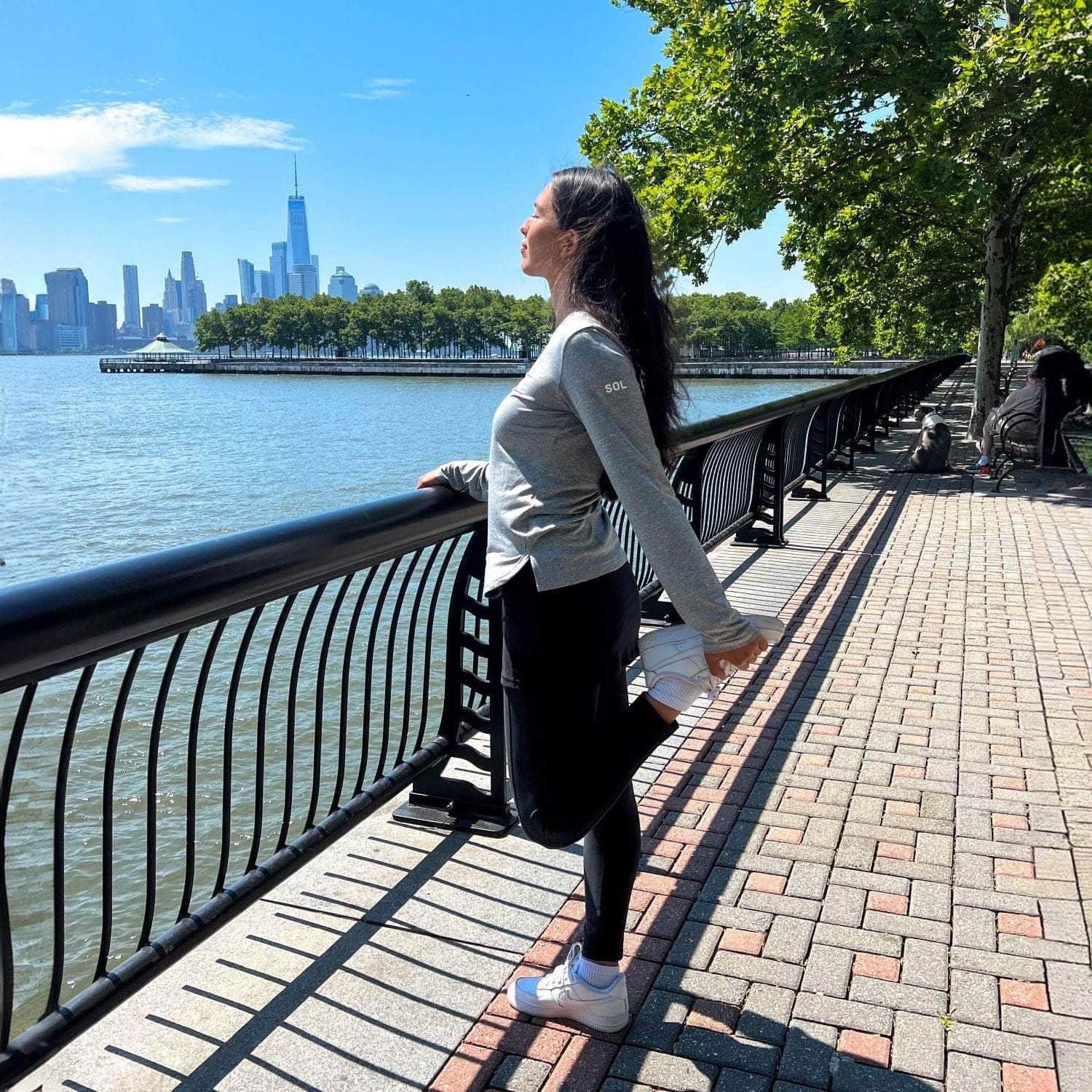 Black ankle length skirted leggings modeled by woman holding handrail near harbor also wearing our grey active sol shirt.