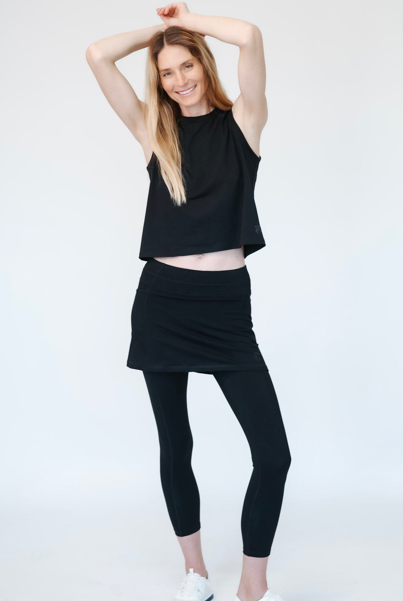 Woman wearing a black cotton tank and black cotton skirted ankle length on a white background