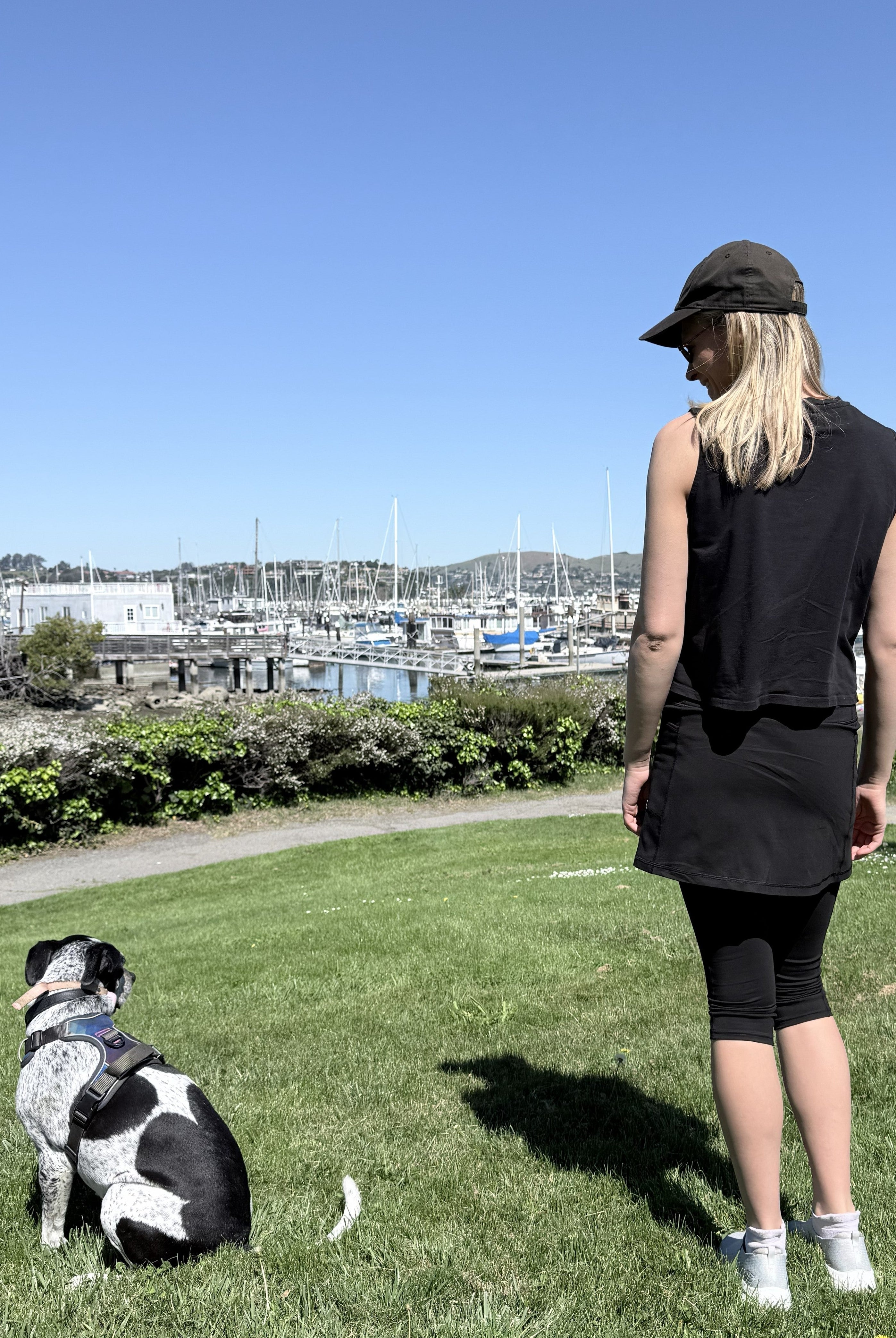 Model wearing black cotton leggings and tank with dog near harbor