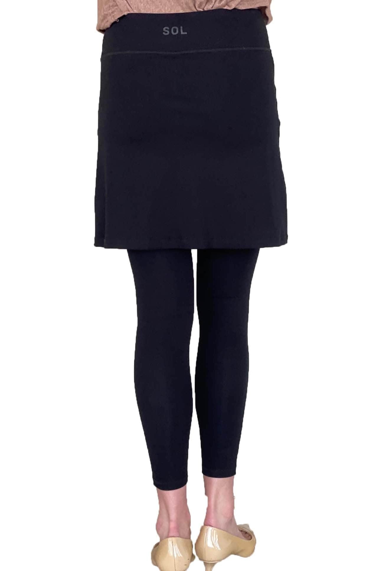 Woman wearing black skirted leggings with 17 inch skirt from back waist down to feet.