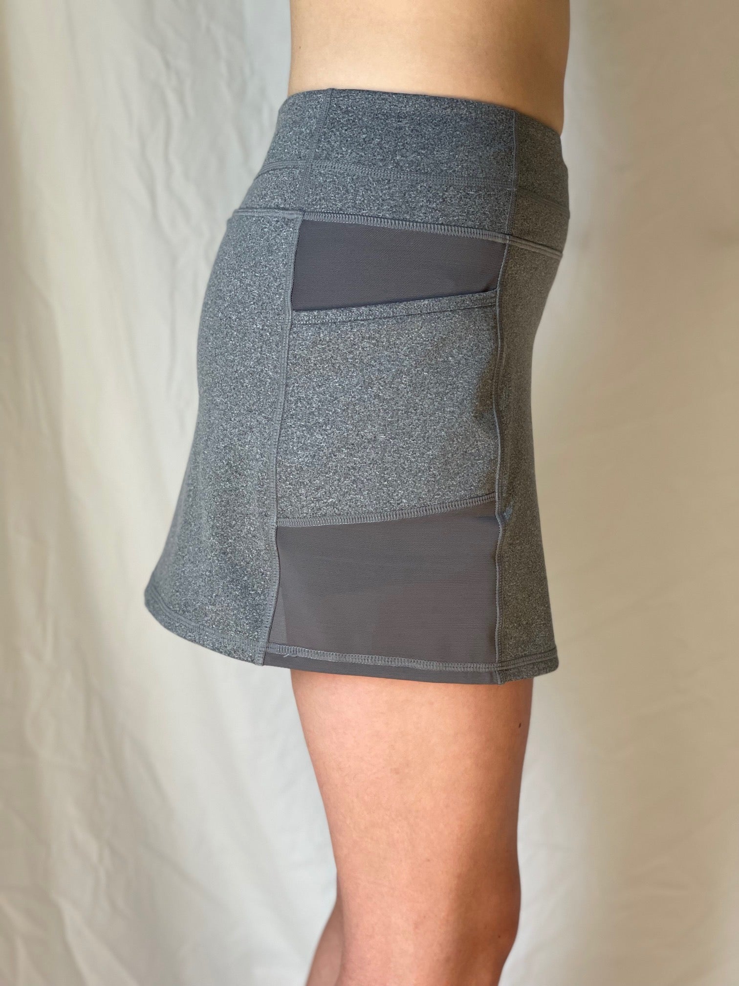 Gray athletic shorts with a pocket on a neutral background. Comfortable, moisture wicking UPF material perfect for tennis, pickleball and golf skort.