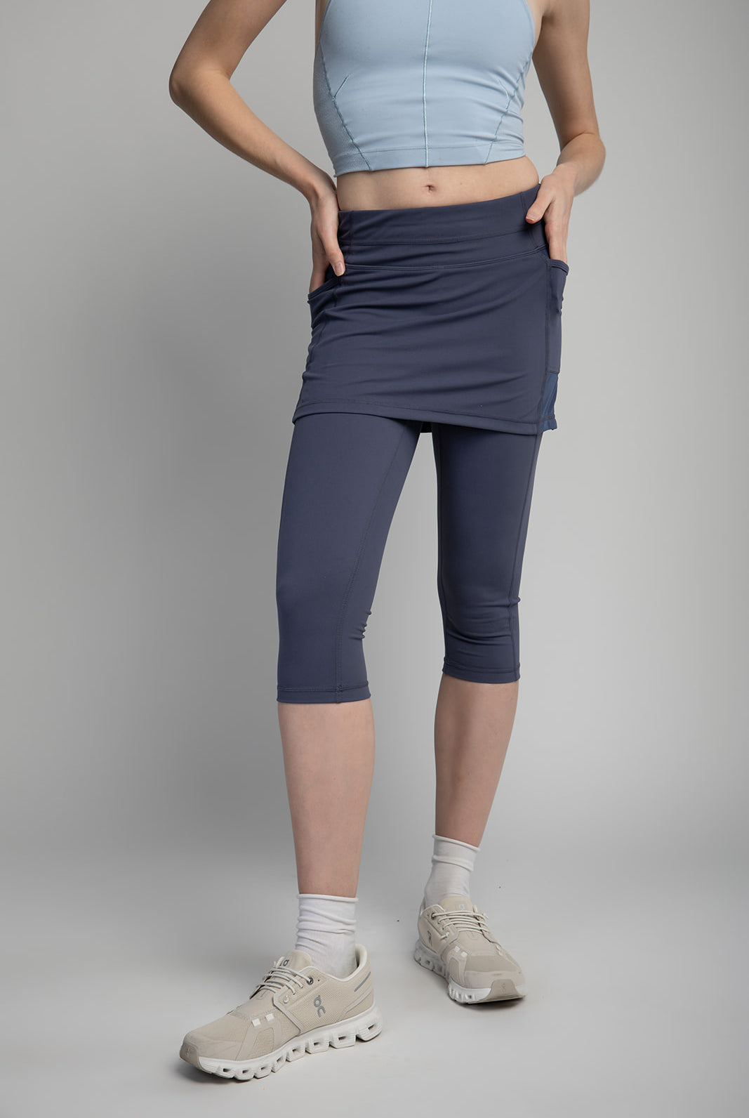 studio shot of model wearing pretty blue grey capris length skirted leggings with light blue halter shirt.