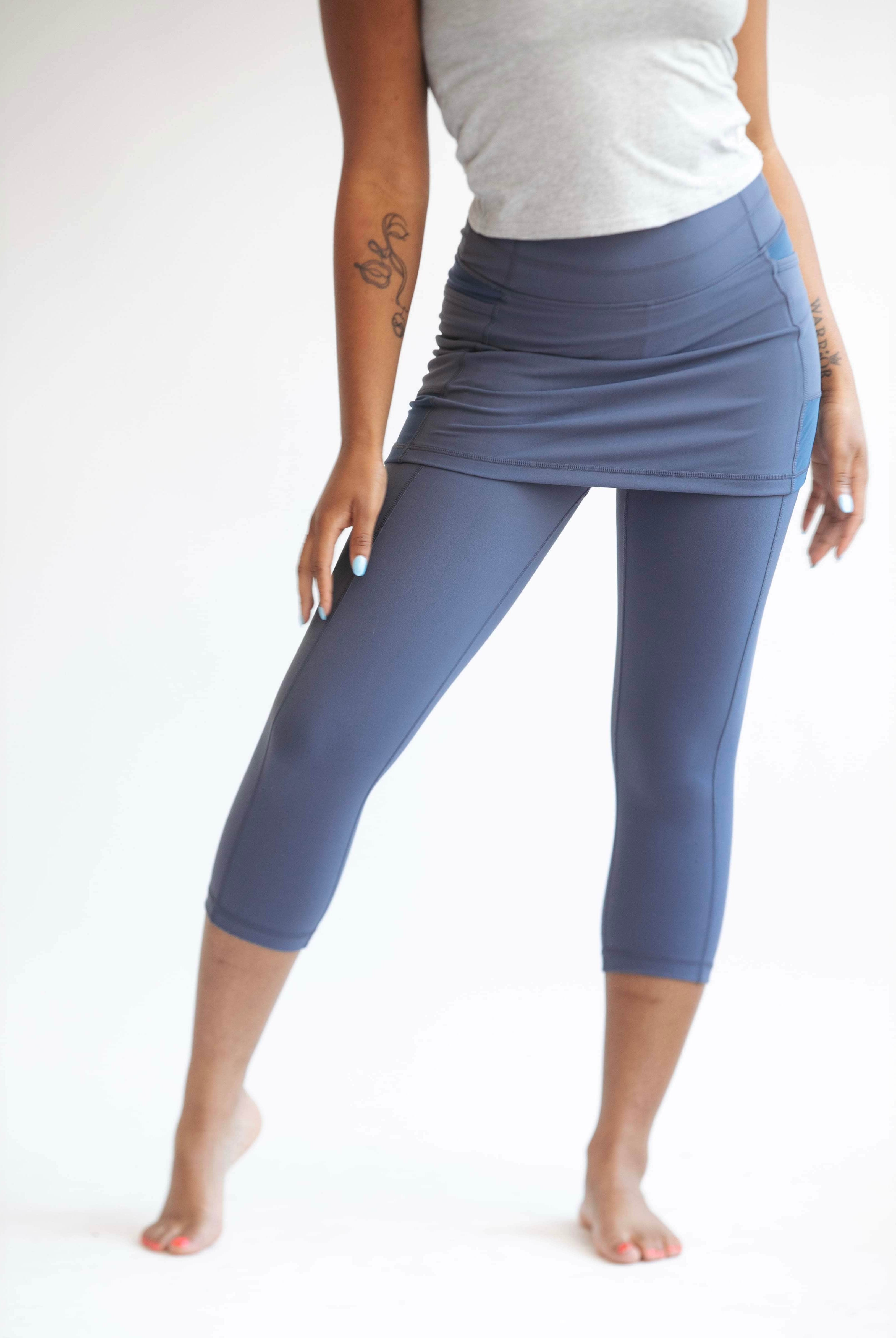 Close up studio shot of model wearing pretty blue grey capris length skirted leggings with light grey t-shirt.