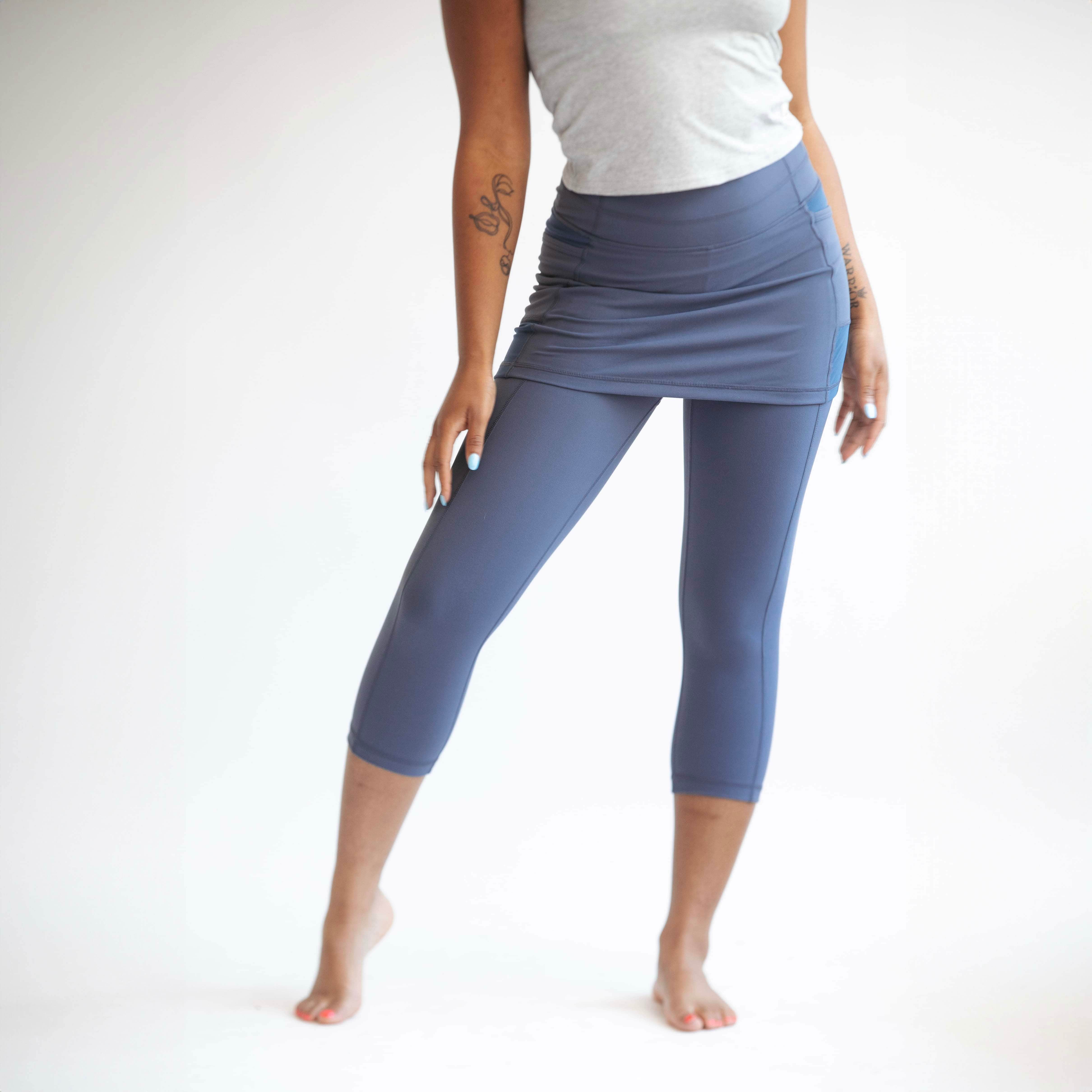 Close up studio shot of model wearing pretty blue grey capris length skirted leggings with light grey t-shirt.