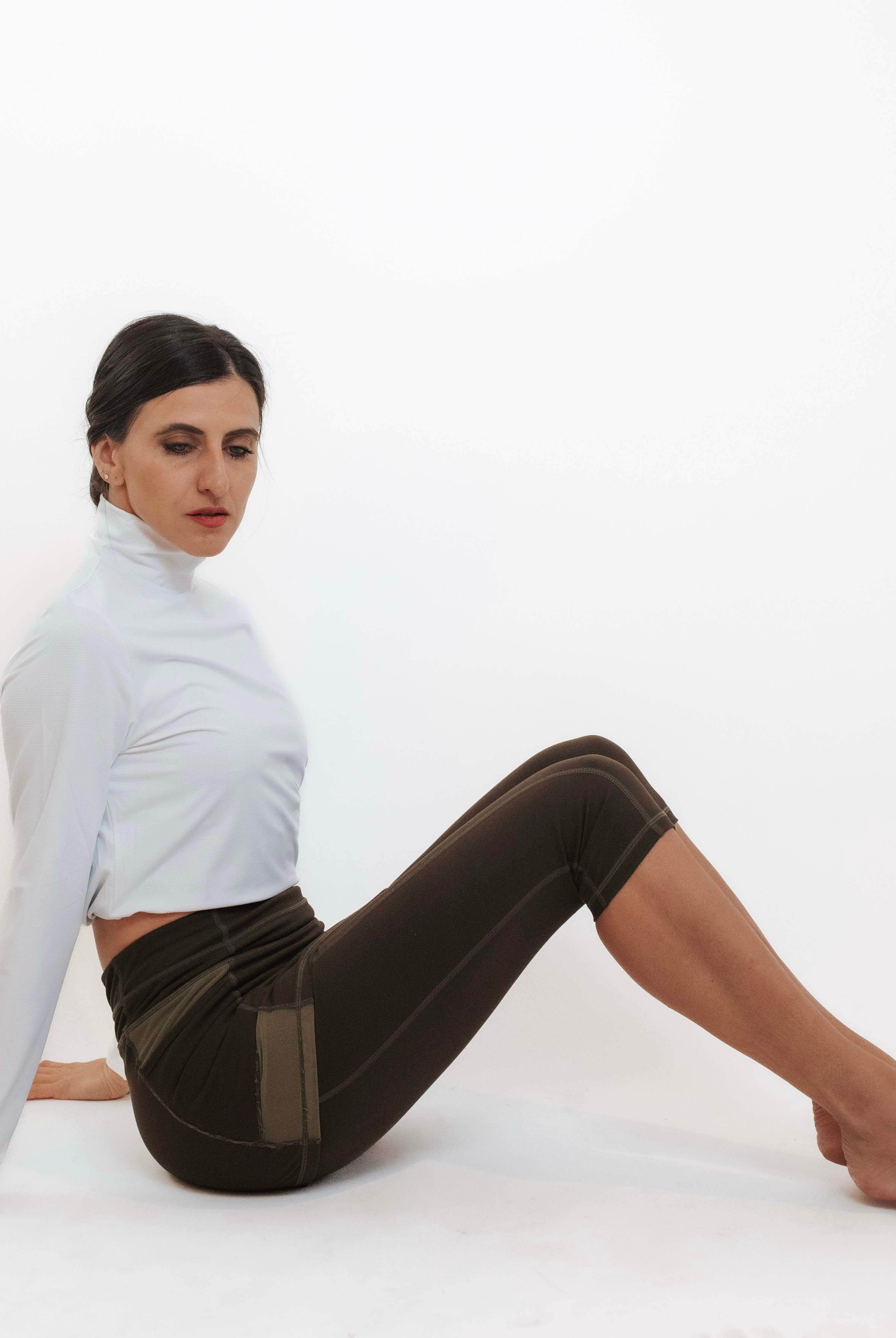 Model sitting in her capris length olive leggings with attached skirt.