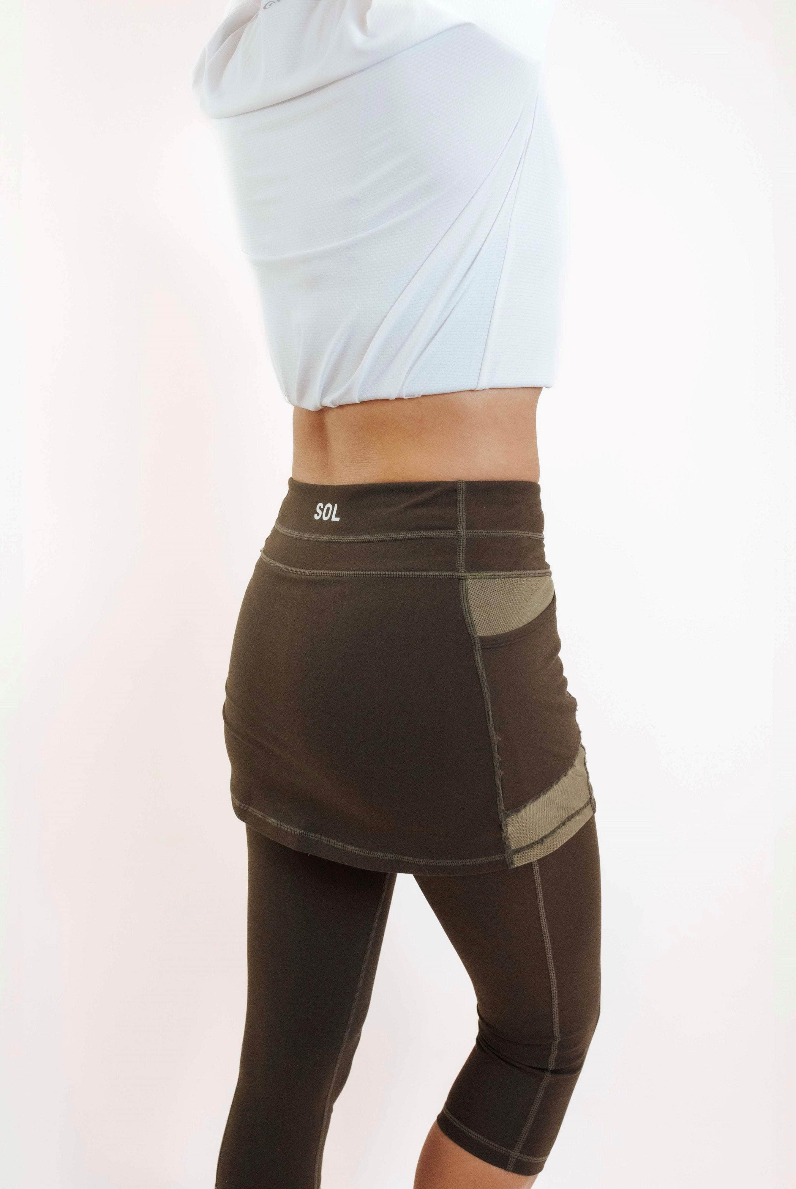 Rear/side view of model wearing capris length dark olive skirted leggings.