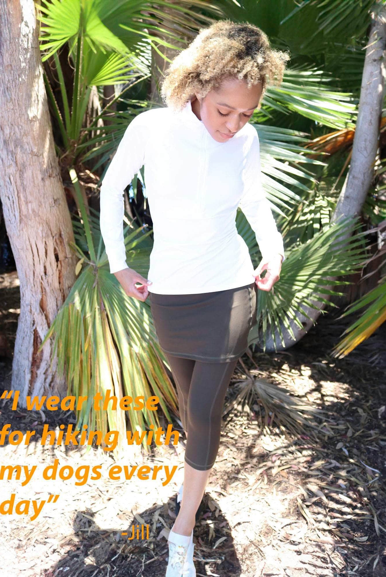 Model in tropical forest wearing capris length olive skirted leggings with white athletic top - Sol SIster Sport