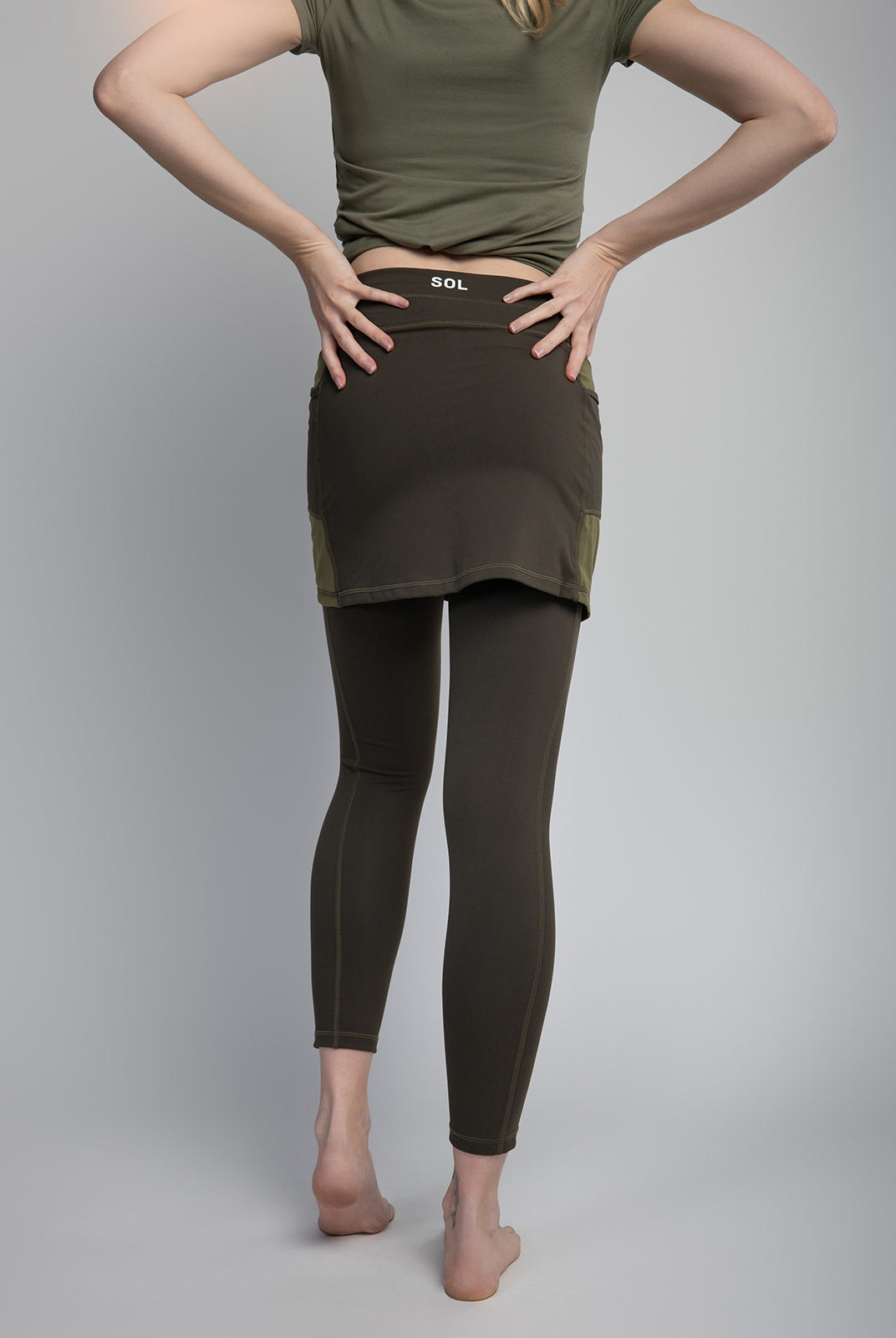 Studio shot of Model wearing 7/8ths length pretty olive skirted leggings