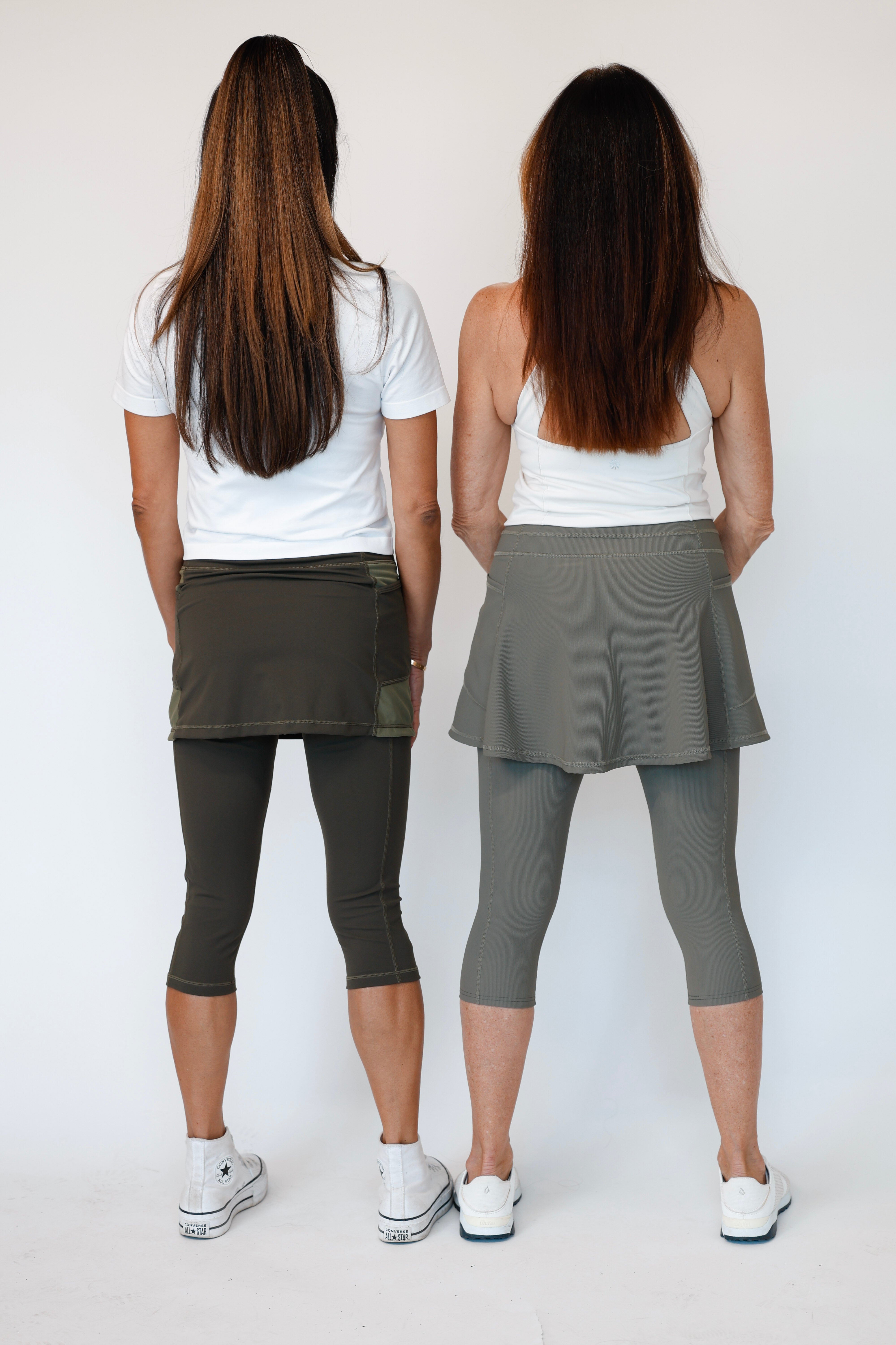 Two women wearing white tops and Olive Capris and Olive Khaki skirted leggings on a white background. Comfortable modest feminine active wear built for travel and built for movement; perfect for tennis, pickleball, golf, yoga, pilates and hiking. UPF sun protective and moisture wicking skirted leggings from a California based women founded and owned athletic wear company called Sol Sister Sport.
