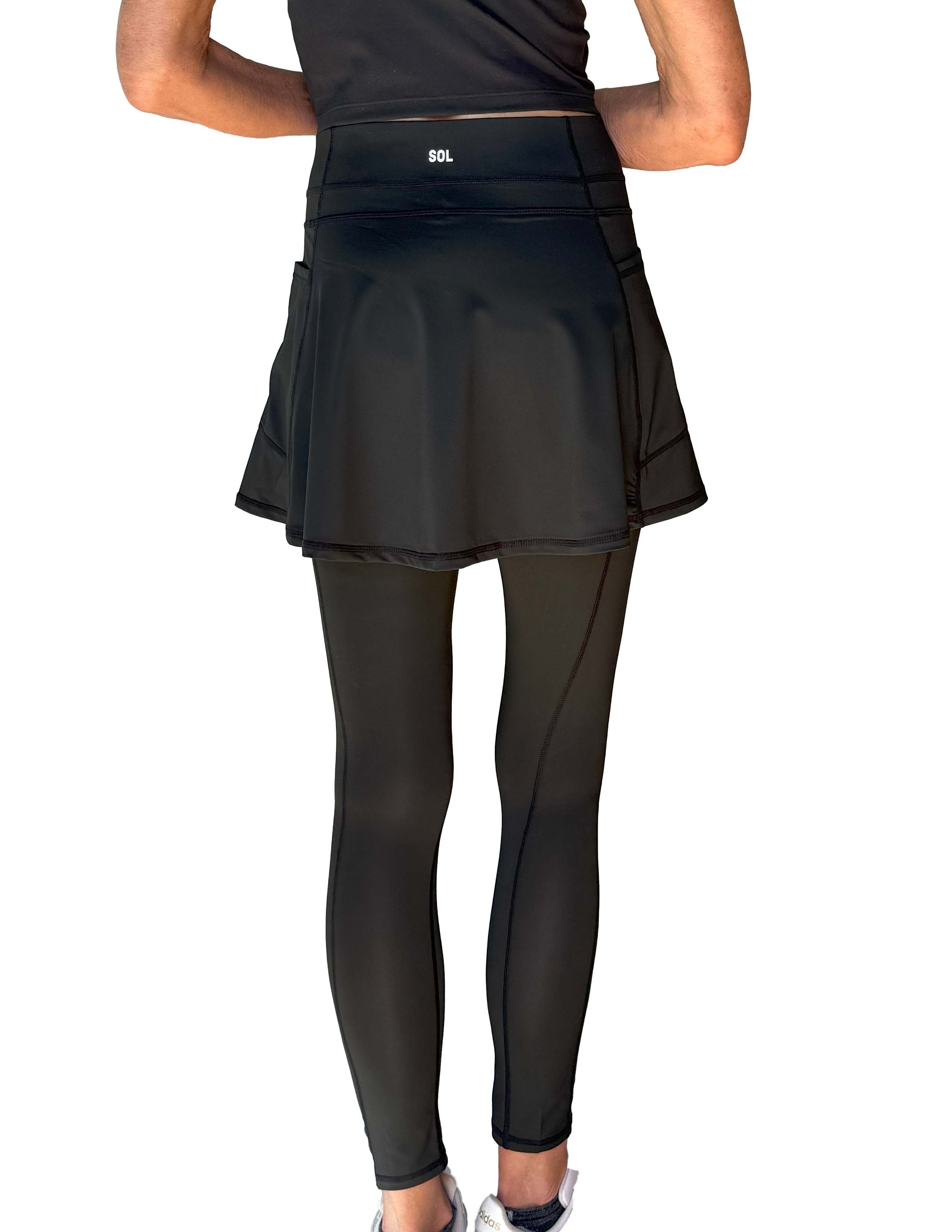 Person wearing a black athletic skirted leggings on a white background from behind