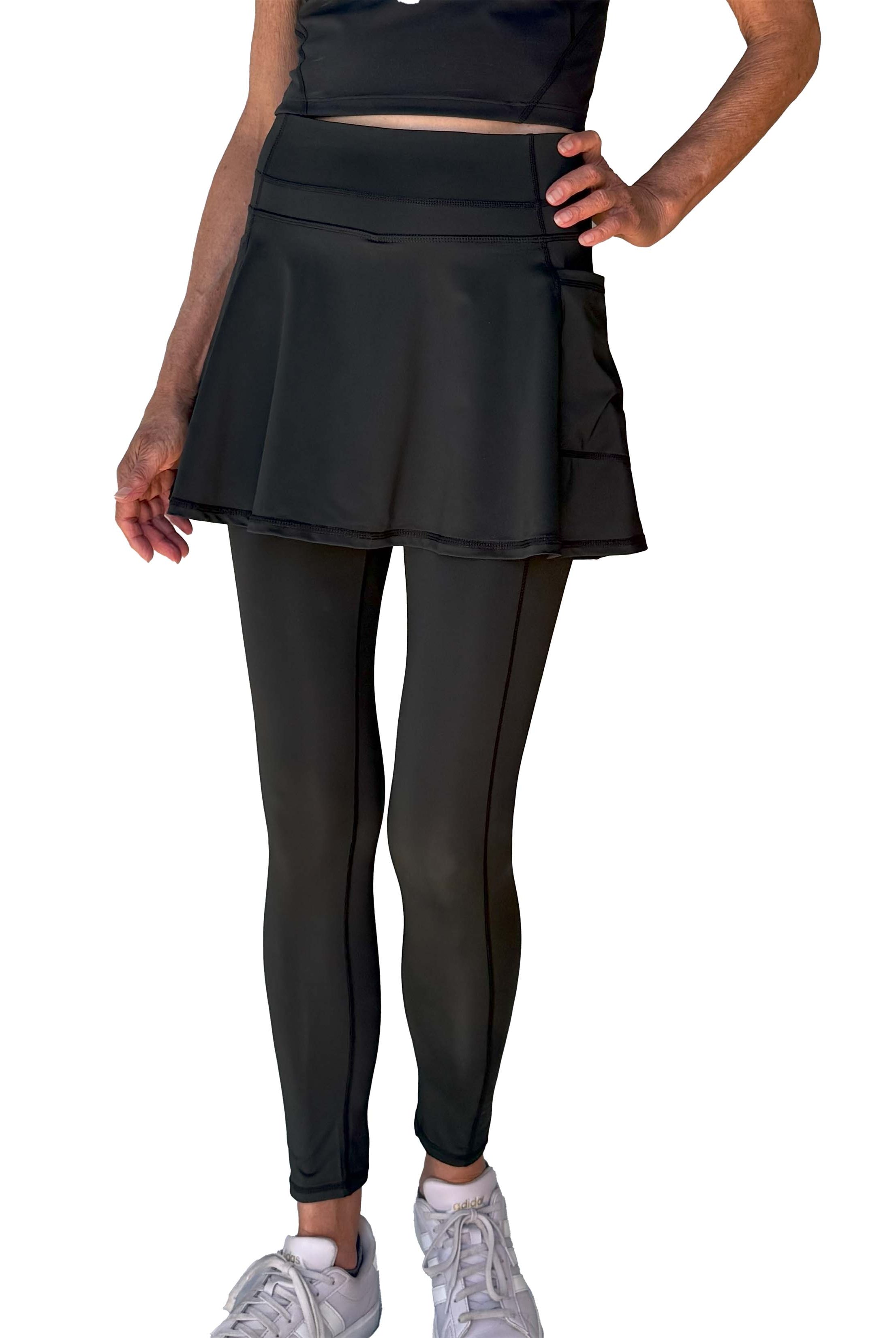 Person wearing a black athletic outfit with 2-1 skirted leggings on a white background