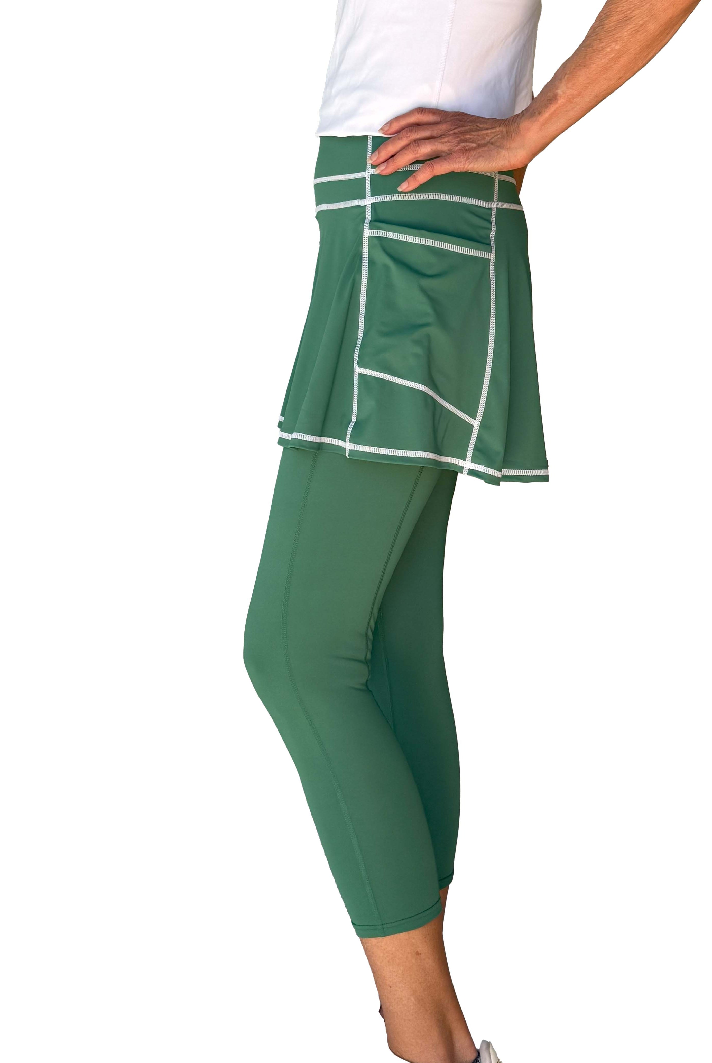 Green athletic skirted leggings with white trim worn by a person on a white background