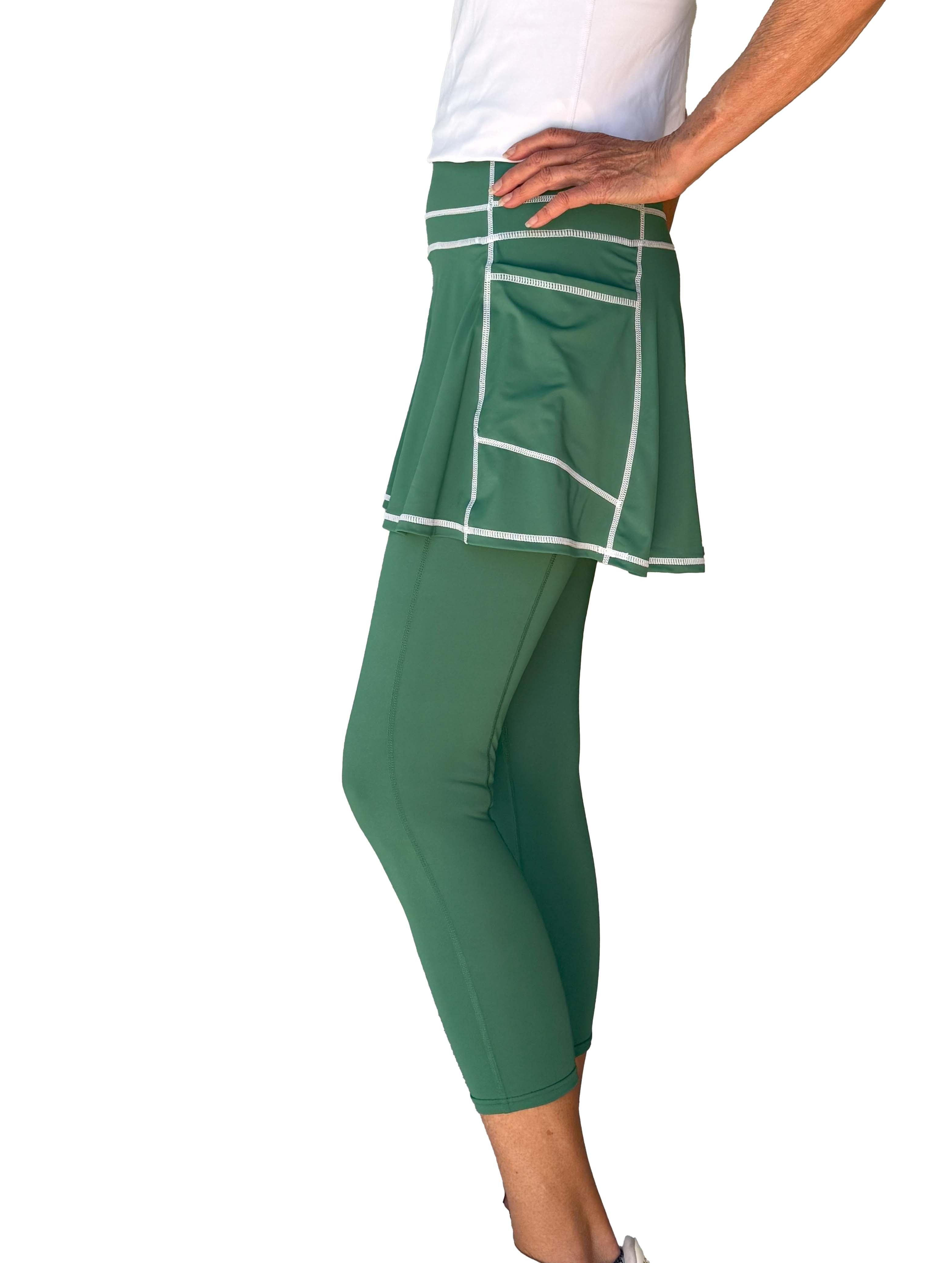 Green athletic skirted leggings with white trim worn by a person on a white background
