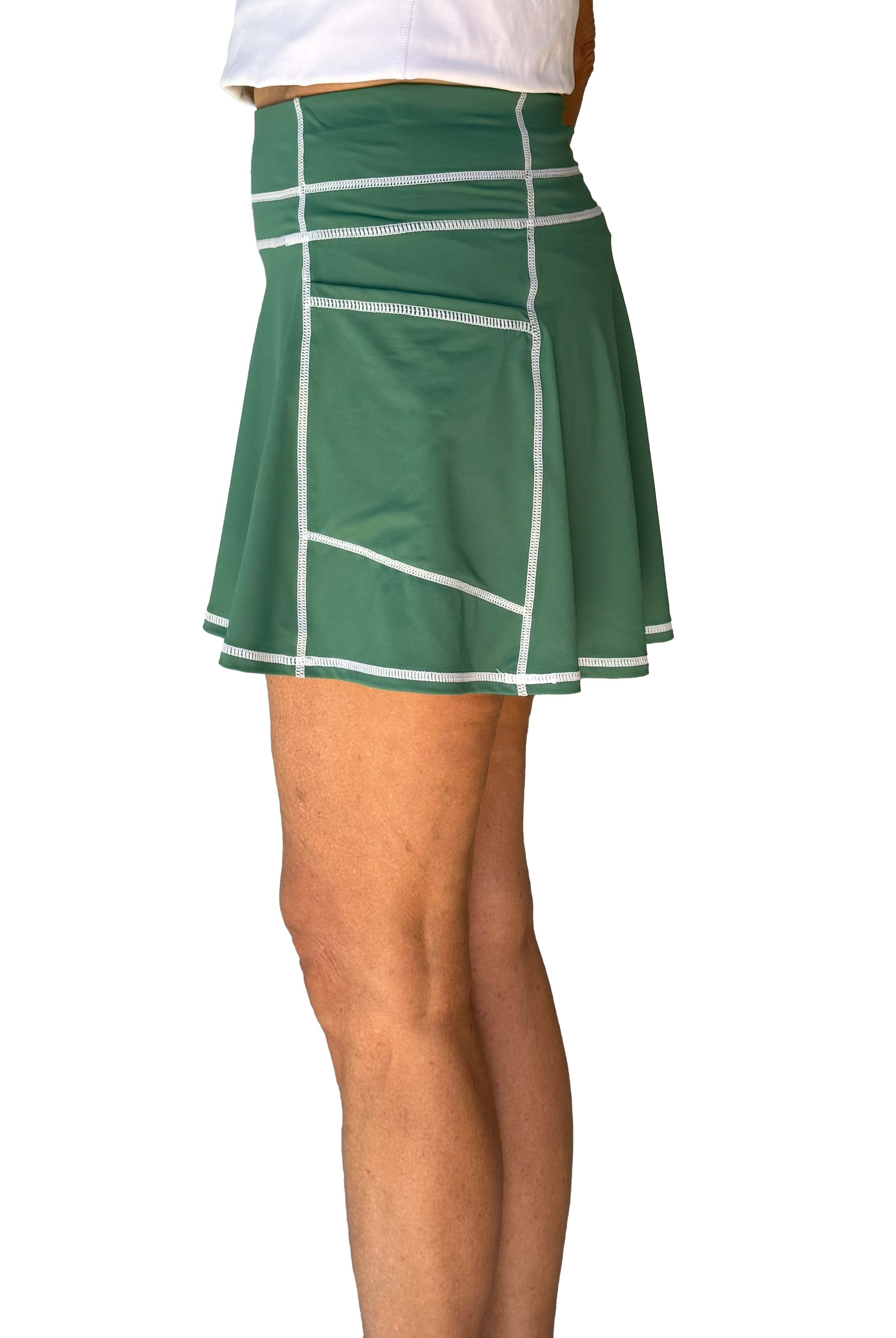 Side view of Green tennis skort with white trim worn by a person on a white background