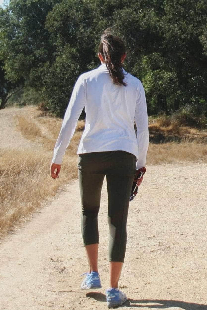 Rear view of model wearing a white Long-sleeve lightweight T-Neck Shirt and olive leggings - Sol Sister Sport