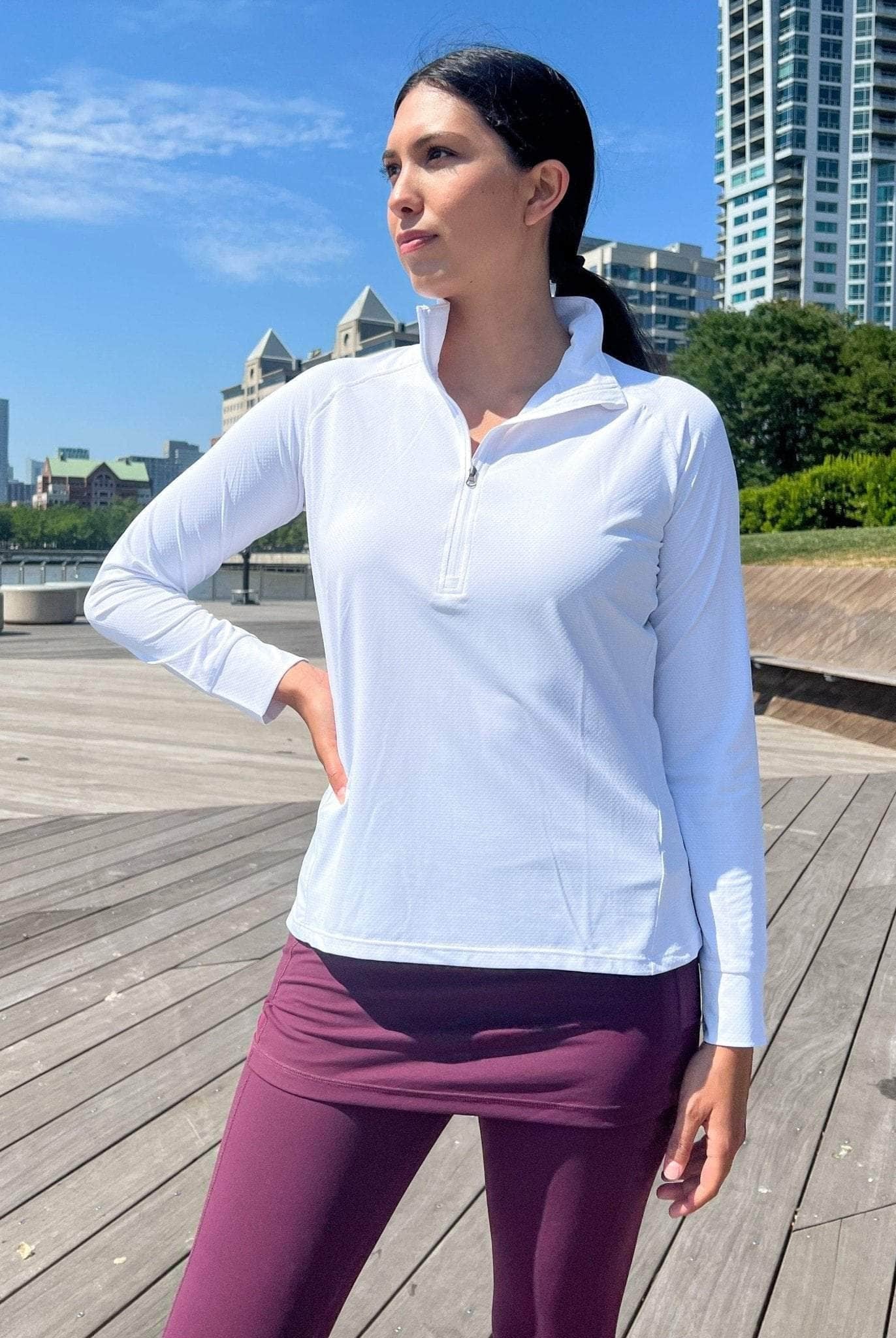 Model wearing a 1/4 zip lightweight white athletic shirt with Maroon skirted leggings