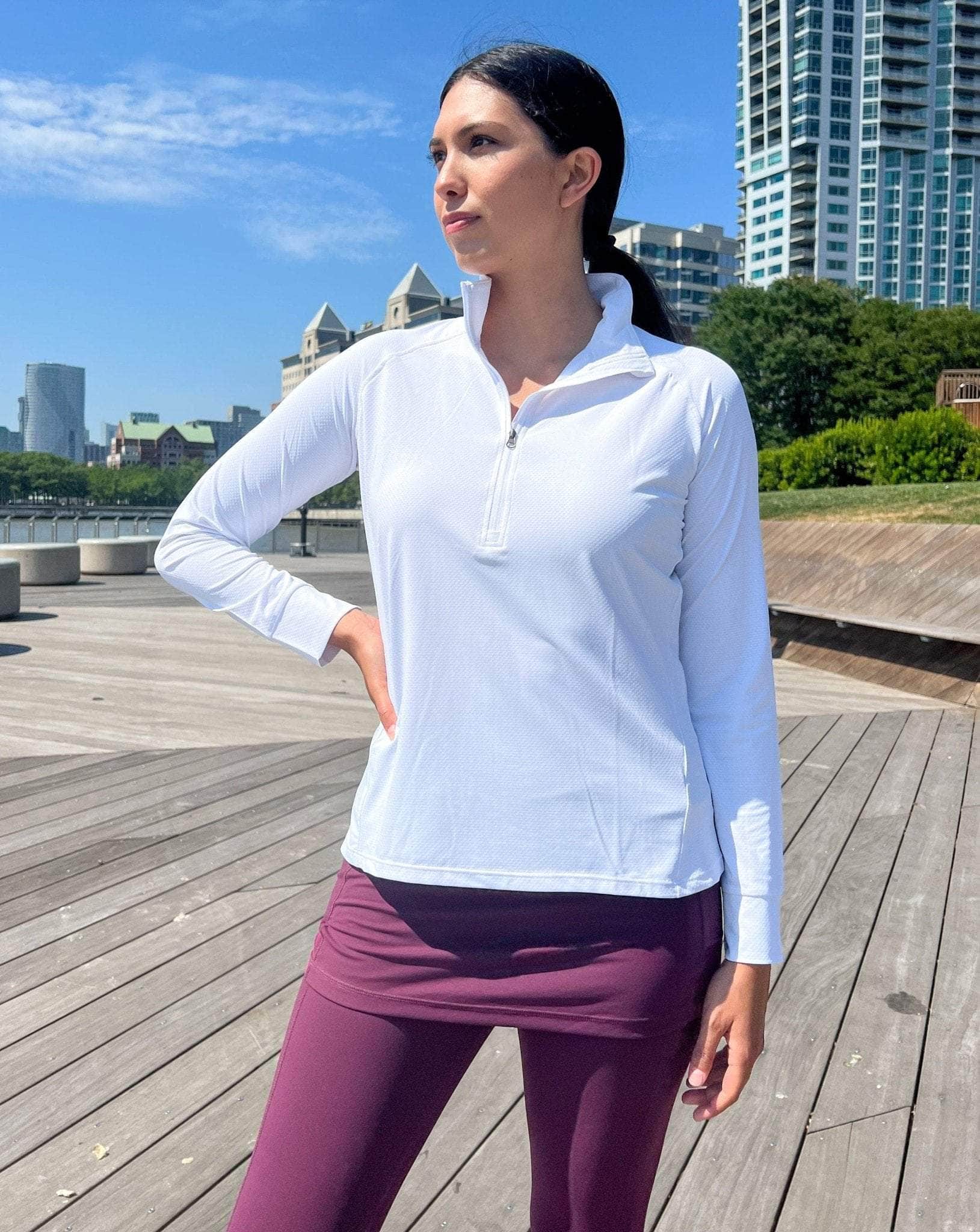 Model wearing a 1/4 zip lightweight white athletic shirt with Maroon skirted leggings