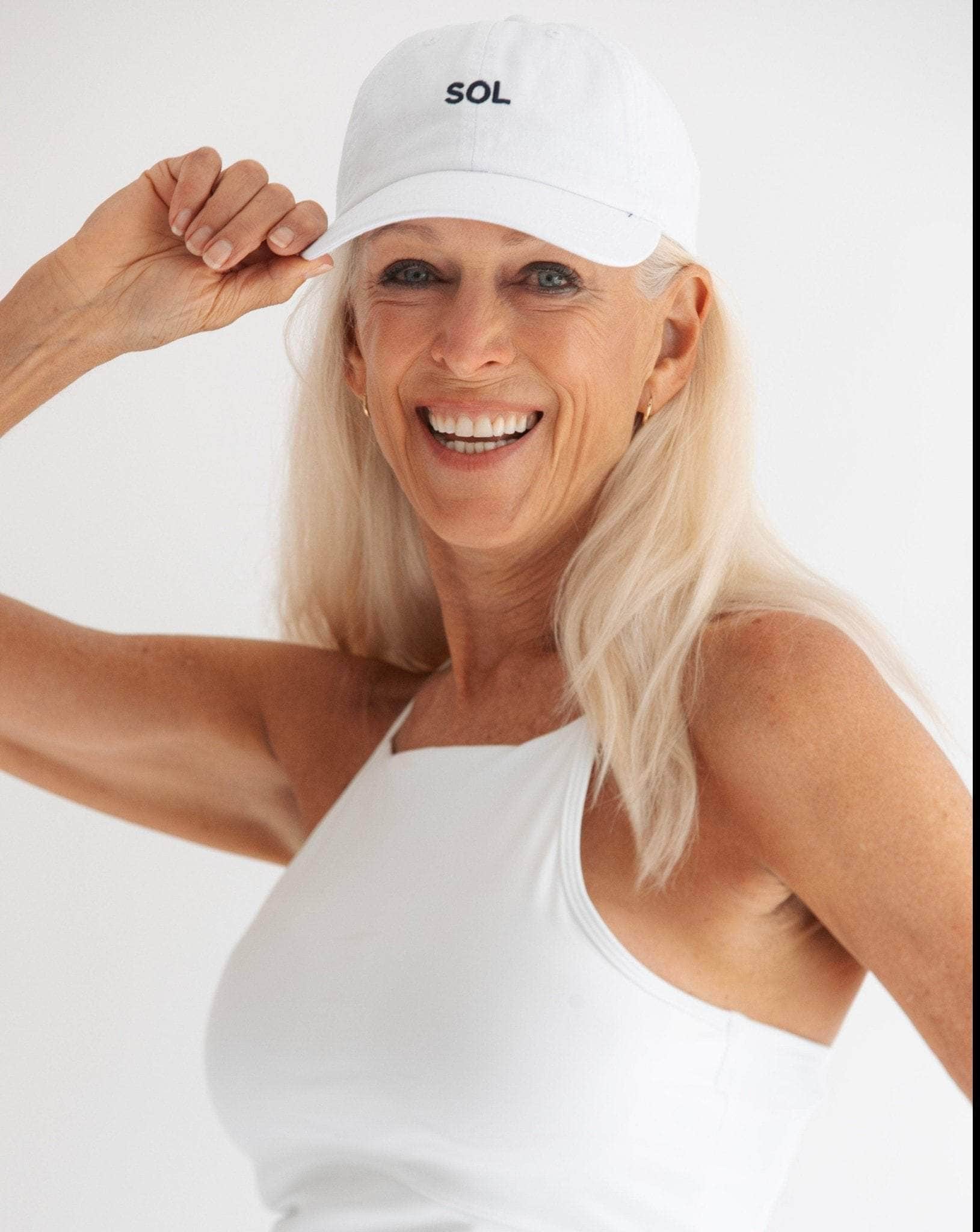 Pretty model wearing White sports Cap with the letters SOL (for sun) on it - Sol Sister Sport