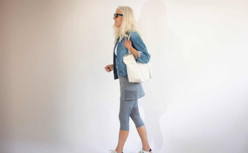 A woman walking with a white bag, showcasing the Best Skirted Leggings for Travel.