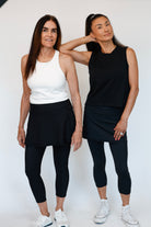 Two women wearing black and white athletic outfits standing against a white background