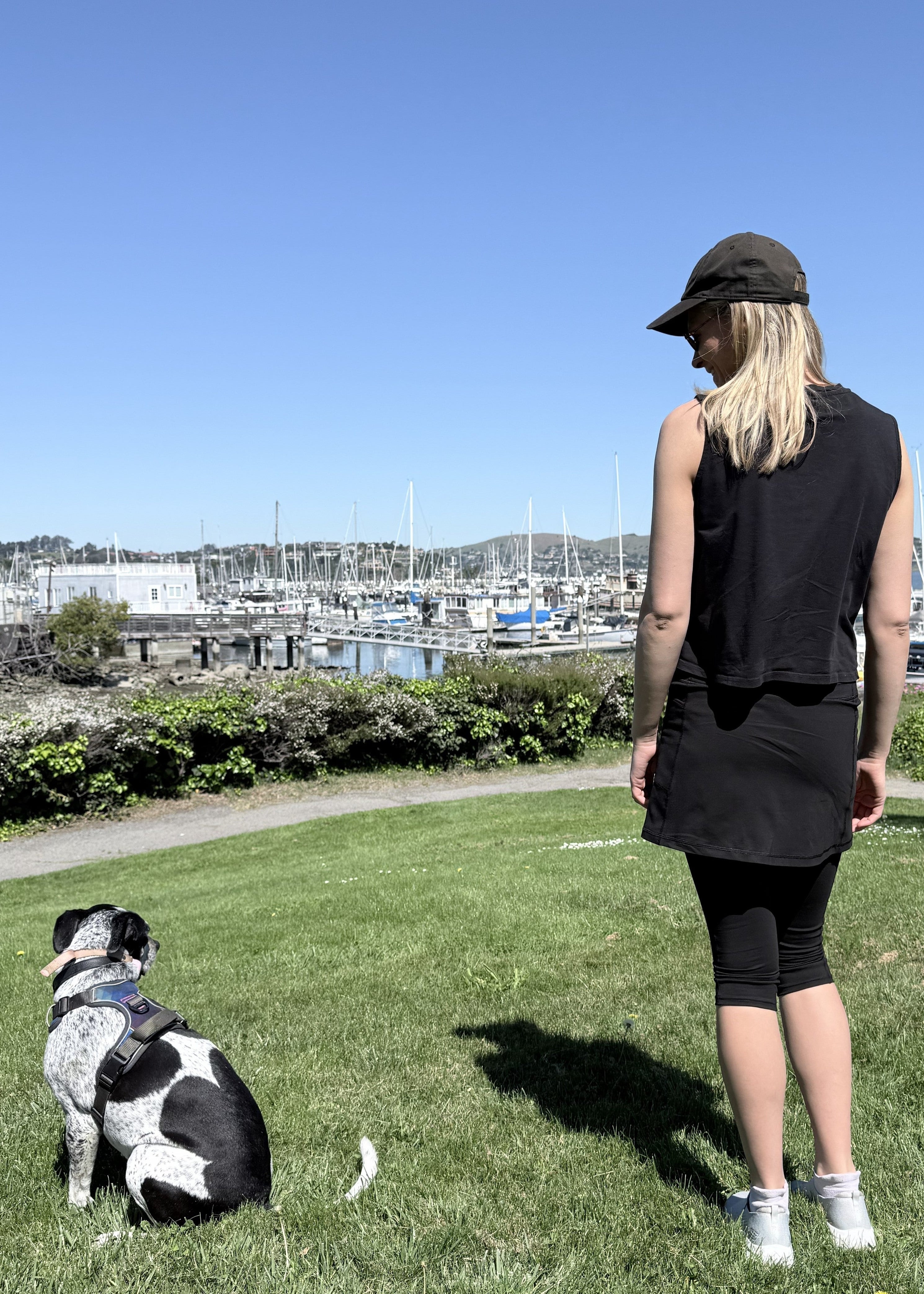 Model wearing black cotton leggings and tank with dog near harbor