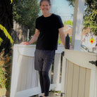 Male model wearing Sol Sister Mister Men's 2-1 Shorts with Leggings with Black T-Shirt.  Front view of model standing in front of gate.