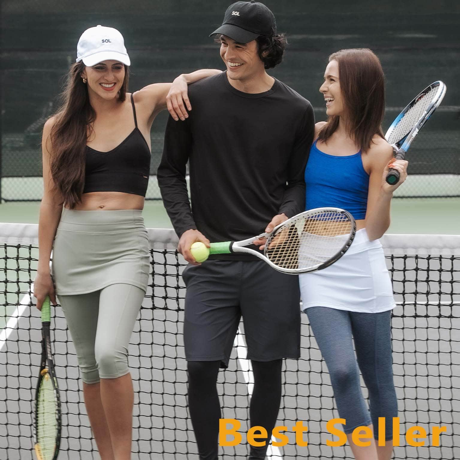 Group shot of 2 feamle models and 1 male model on tennis court wearing skirted leggings and the male model is wearing black leggings with attached shorts.s.