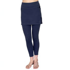 Woman wearing dark blue 7/8th legging length skirted leggings from waist down with white background from front view.