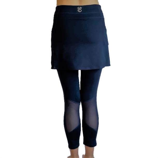 Woman wearing Navy mid-calf legging length skirted leggings from waist down with white background from back view.