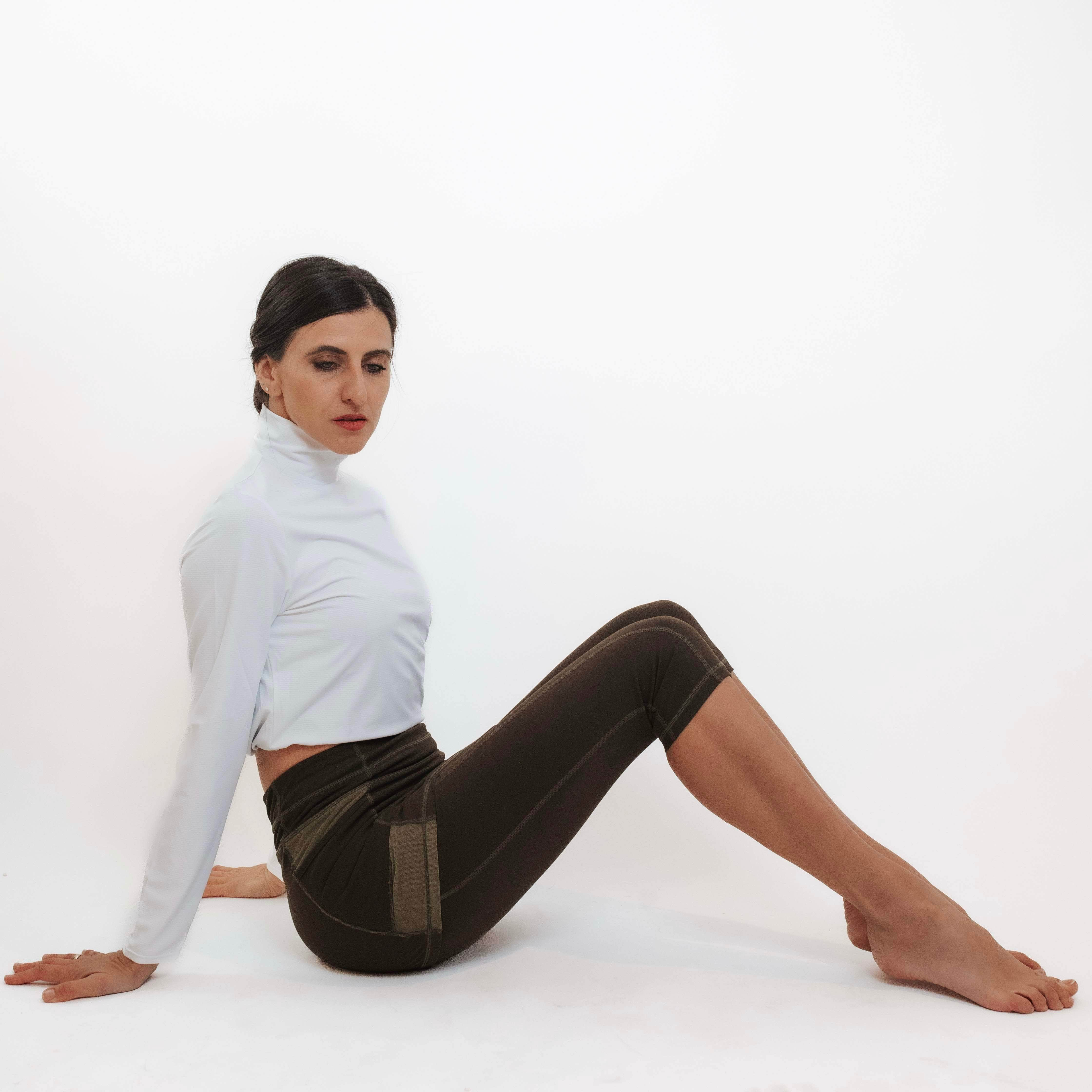 Model sitting in her capris length olive leggings with attached skirt.