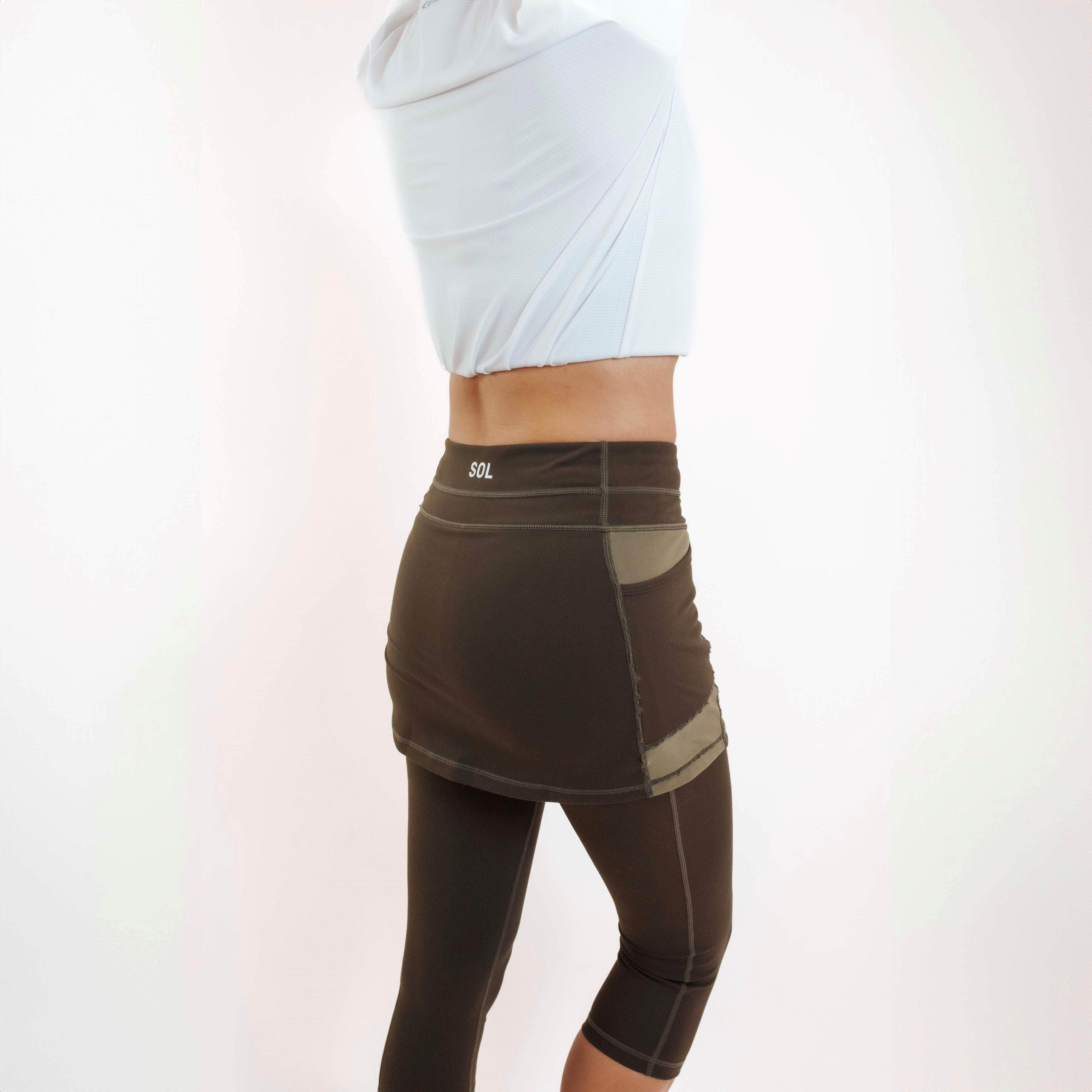 Rear/side view of model wearing capris length dark olive skirted leggings.