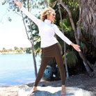 Model wearing 7/8ths length pretty olive skirted leggings with white athletic top.  Outdoors on beach.