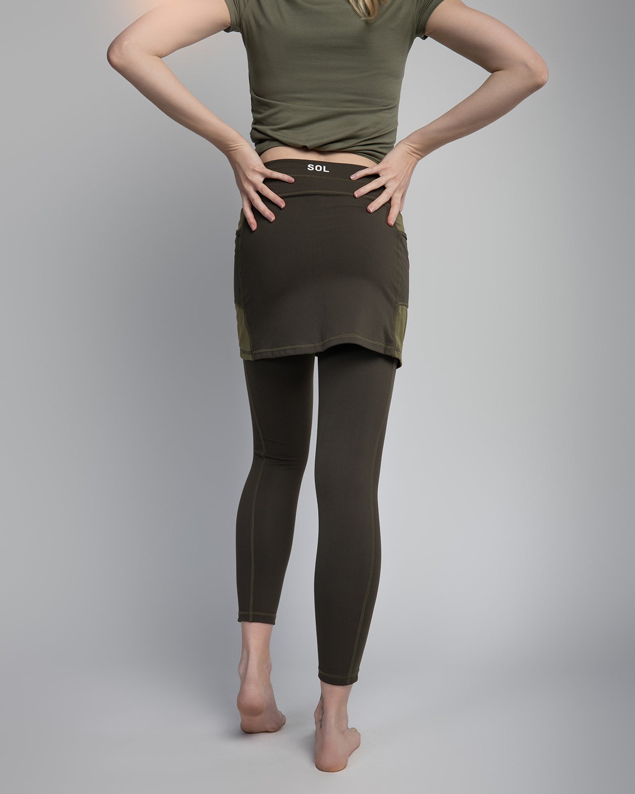Studio shot of Model wearing 7/8ths length pretty olive skirted leggings 