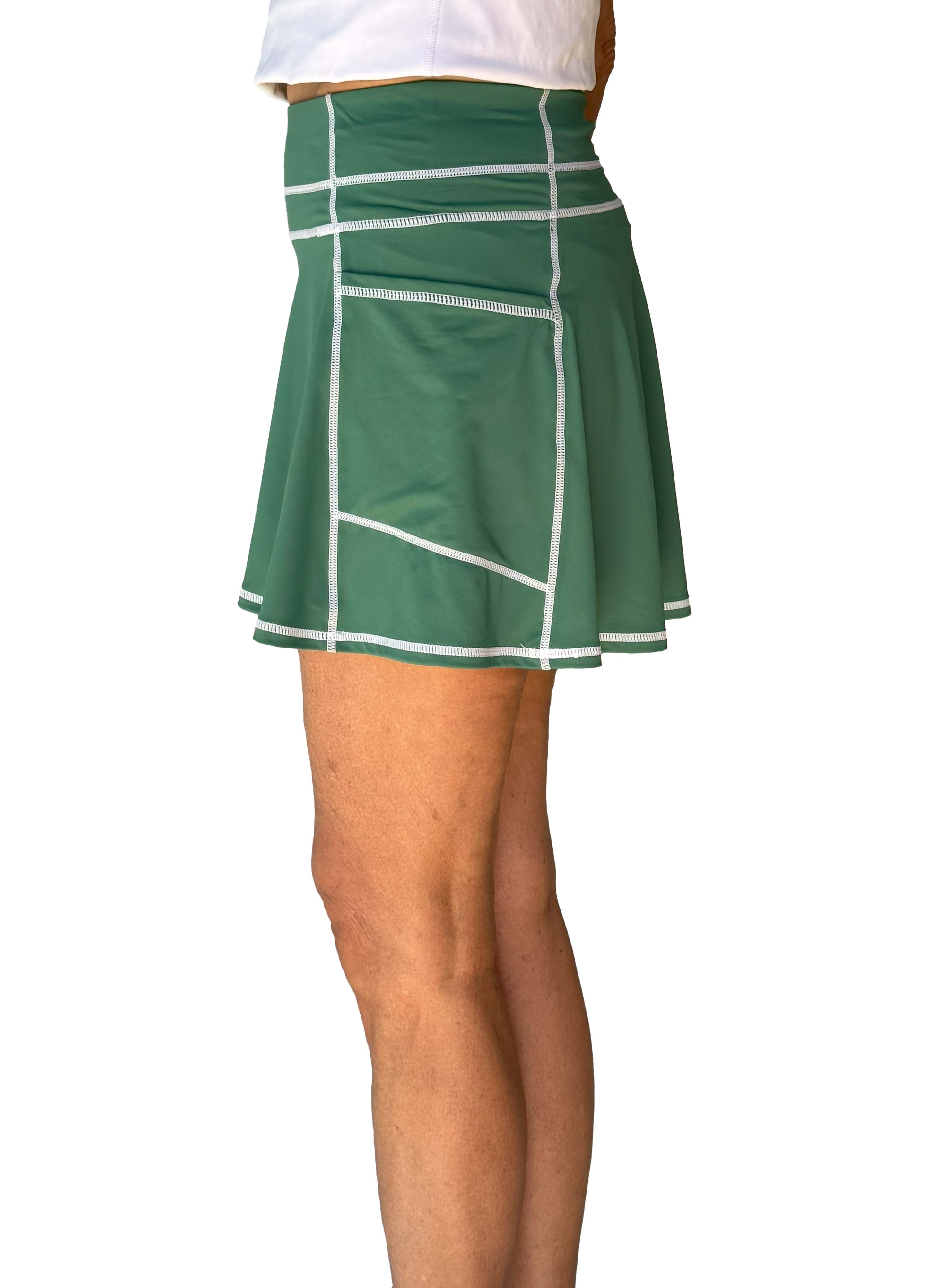Side view of Green tennis skort with white trim worn by a person on a white background