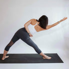 Studio shot of model wearing 3/4 length steel colored skirted leggings while doing yoga.