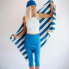 Smiling model is holding a blue and white beach towel while wearing a pretty bright blue swim skirted legging - water activity skirt.