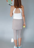 Woman holding a tennis racket and ball against a plain background