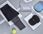 2-1 Black and Grey Sport Skort Capris Leggings lying flat with grey SOL shirt, black SOL baseball cap, pickleball paddle and pickleball.