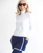 Smiling woman wearing navy skirted leggings with white piping on skirt and white athletic top.