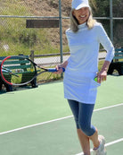 Model is wearing heather blue leggings with attached white skirt with deep pockets on tennis court. Sol Sister Sport