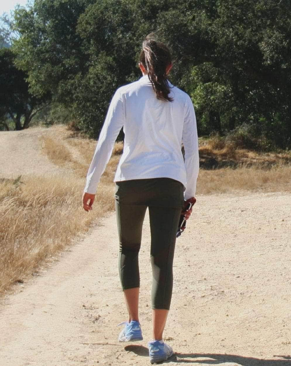 Rear view of model wearing a white Long-sleeve lightweight T-Neck Shirt and olive leggings - Sol Sister Sport